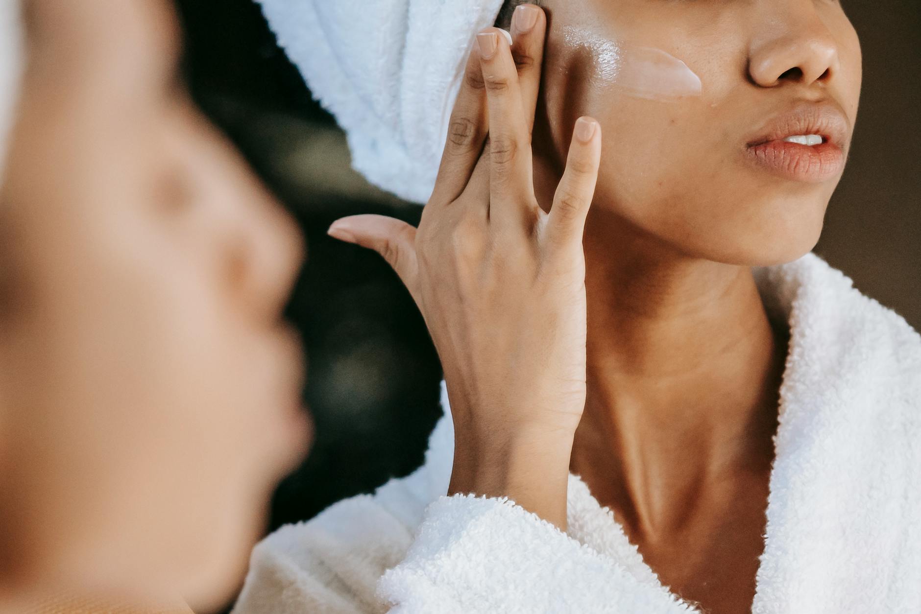 woman applying cream on face to Transition Your Skincare Routine from Summer to Fall