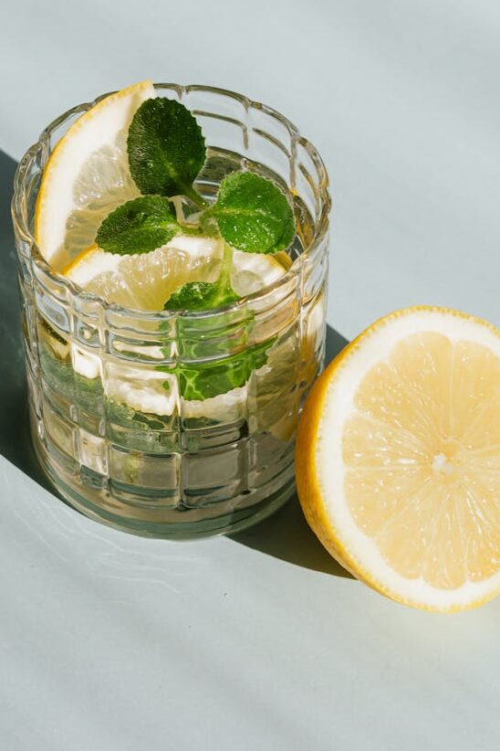 glass of refreshing drink on table - lemon water self care essentials