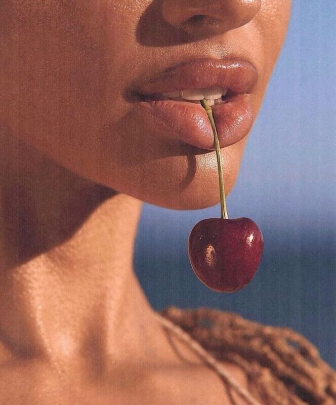 woman holding a cherry in her mouth