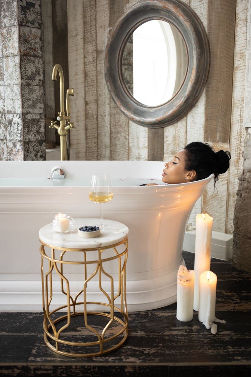 ethnic woman lying in bathtub in bathroom with candles